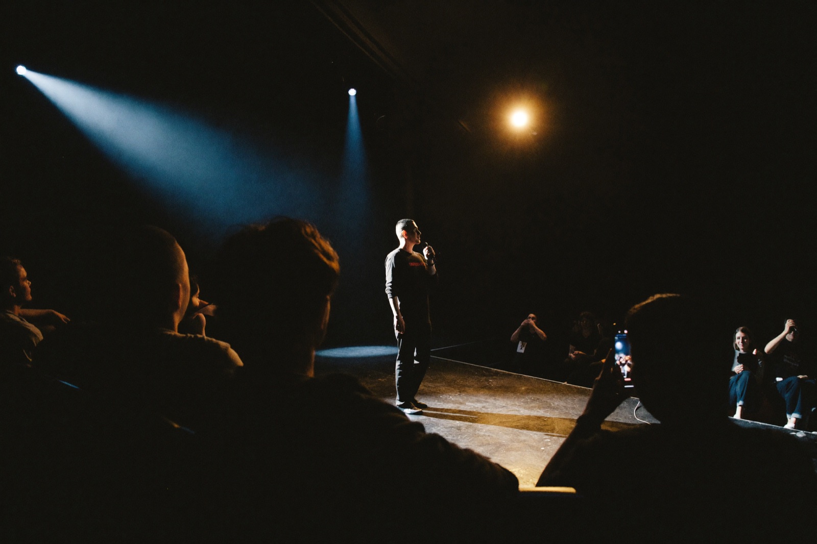 Stand-up na pódiu v divadle, divák natáča z hľadiska
